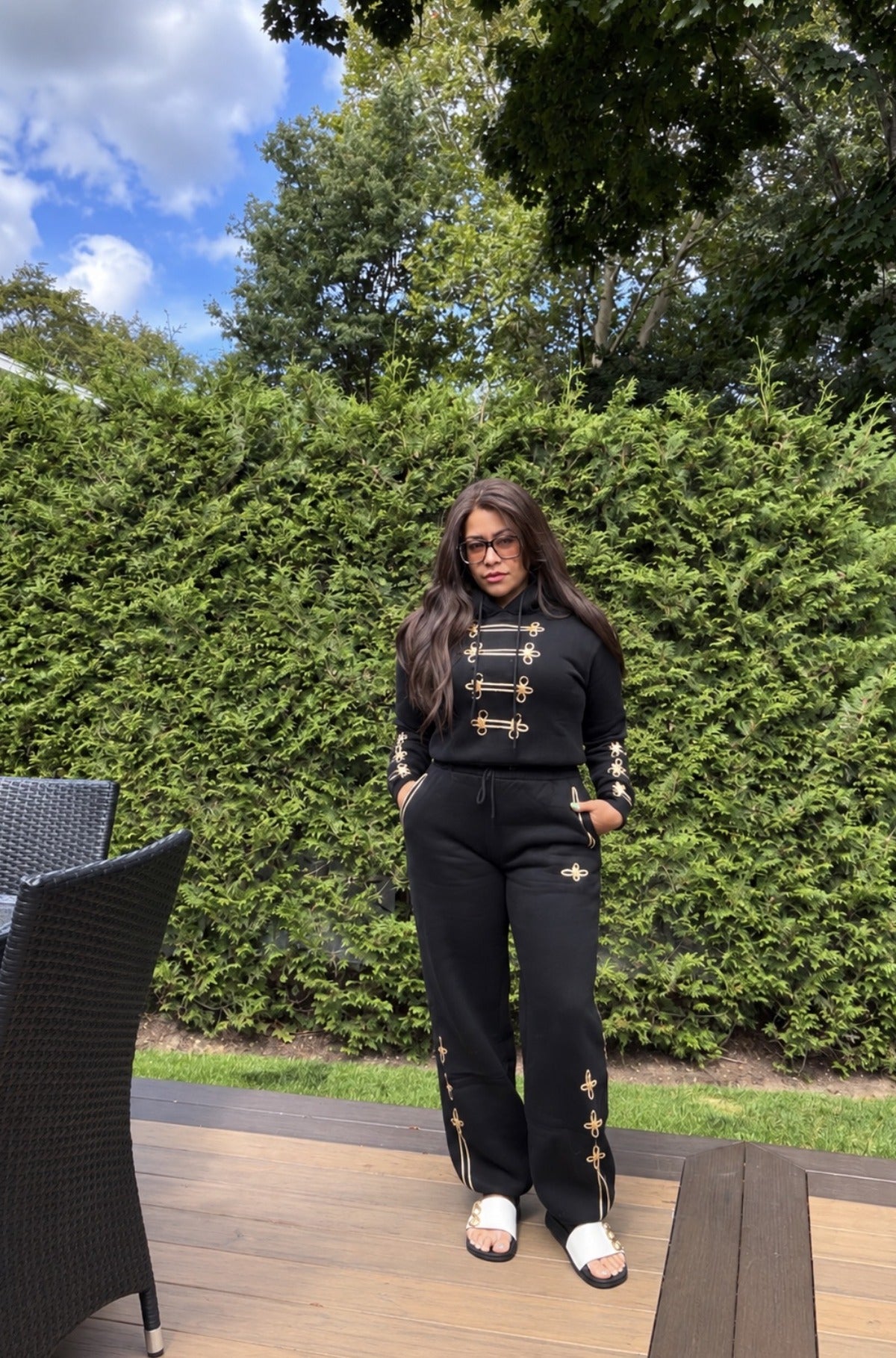 The Gilded Rebellion Set worn full-length with the trouser cuff down, black hoodie and trouser with gold military detailing