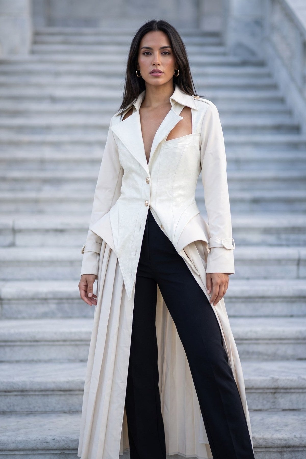 The Scala Corset Coat half-buttoned over black wide-leg trousers, showing the pointed front hem and buckled cuff tabs